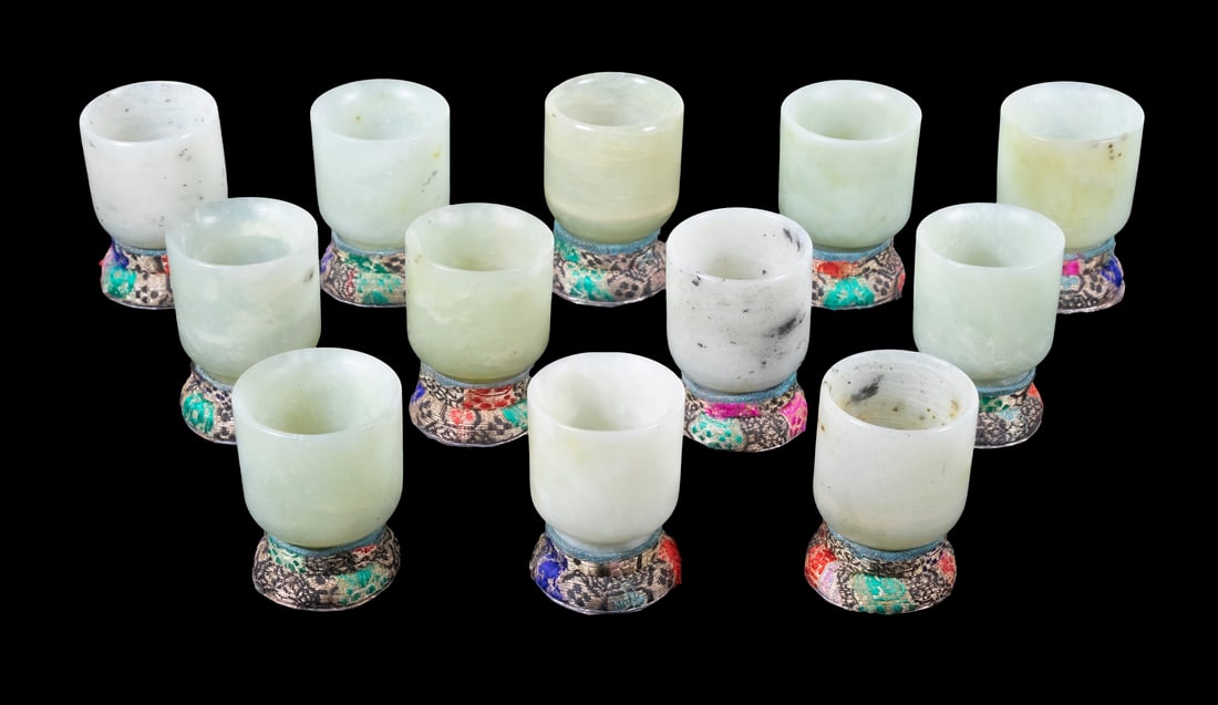 CASED SET OF CARVED HARDSTONE CUPS: Set of (12) 20th c. Hardstone Wine Cups, in mottled celadon, each 1 1/4" high, in a fabric covered presentation case, 2" x 12 1/2" x 6". Case exterior surface wear.
