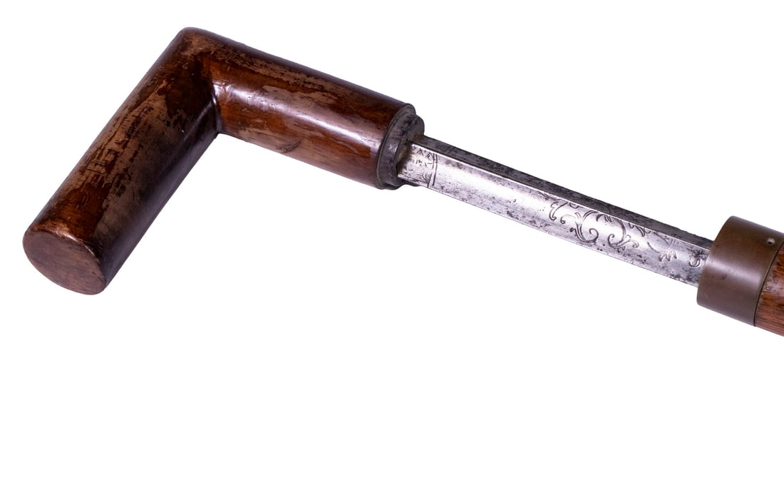 18TH C. SWORD CANE: Gent's Macassar Wood Walking Stick, with brass bands, having an enclosed triangular blade sword with engraved scrolled decoration, 34 1/2" long, blade only: 27 1/2" long.