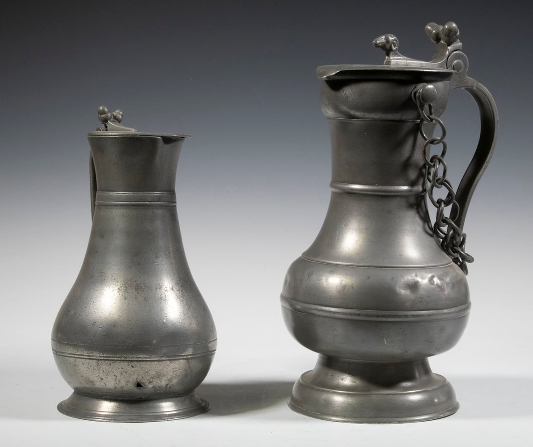 EARLY PEWTER FLAGONS: Lot of (2) 18th - 19th c. Drinking Vessels, incl: Continental baluster shape flagon, with raised body bands, double acorn thumb lift and ram's head lid finial, link chain attached to two lugs at the n