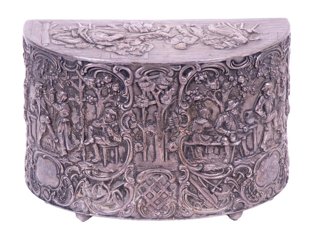 SILVER PLATE TOBACCO BOX BY MARK CROSS & CO., LONDON: Circa 1920s Demilune Shape Swing Drawer Cigarette Box, with repousse figural village and tavern scenes to lid and front panel, leather back with applied silver-plate monogram, set on ball feet, 5" hig