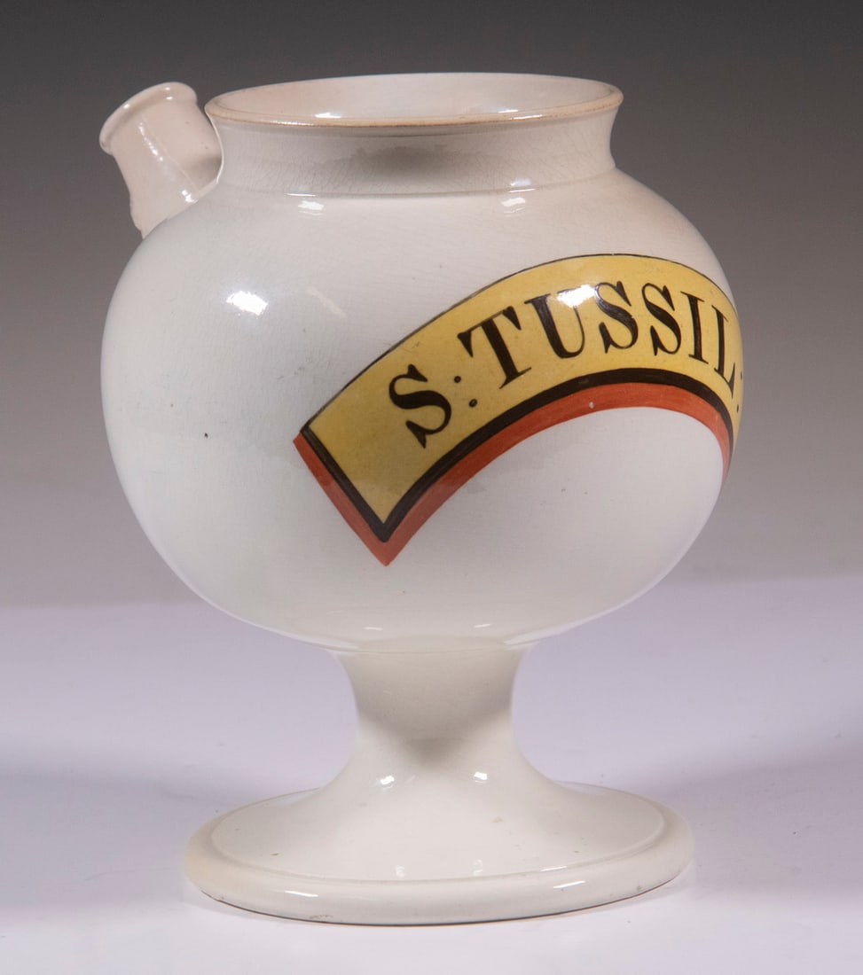 CREAMWARE APOTHECARY SYRUP JAR: Early 19th c. English Pottery Pharmaceutical Jug, having a spout with molded Bacchus mask, painted "S. Tussil" label, 7 1/2" high, 7 1/2" x 6".
