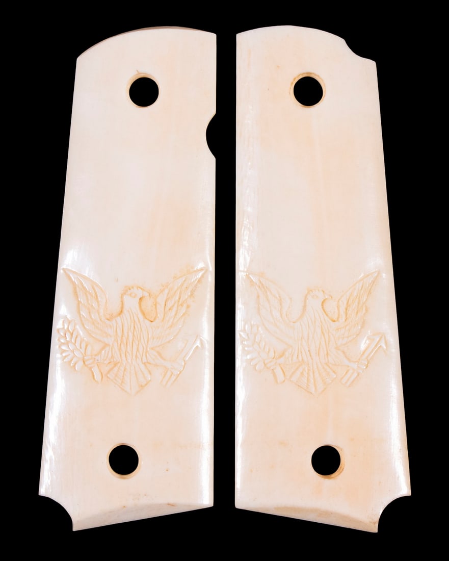 CUSTOM MADE IVORY 1911 GRIP PANELS: A beautiful pair of custom made ivory grip panels by an unknown maker. Both panels feature an engraving of the U.S. bald eagle clutching olive branch and arrows and are marked "50" on their undersides