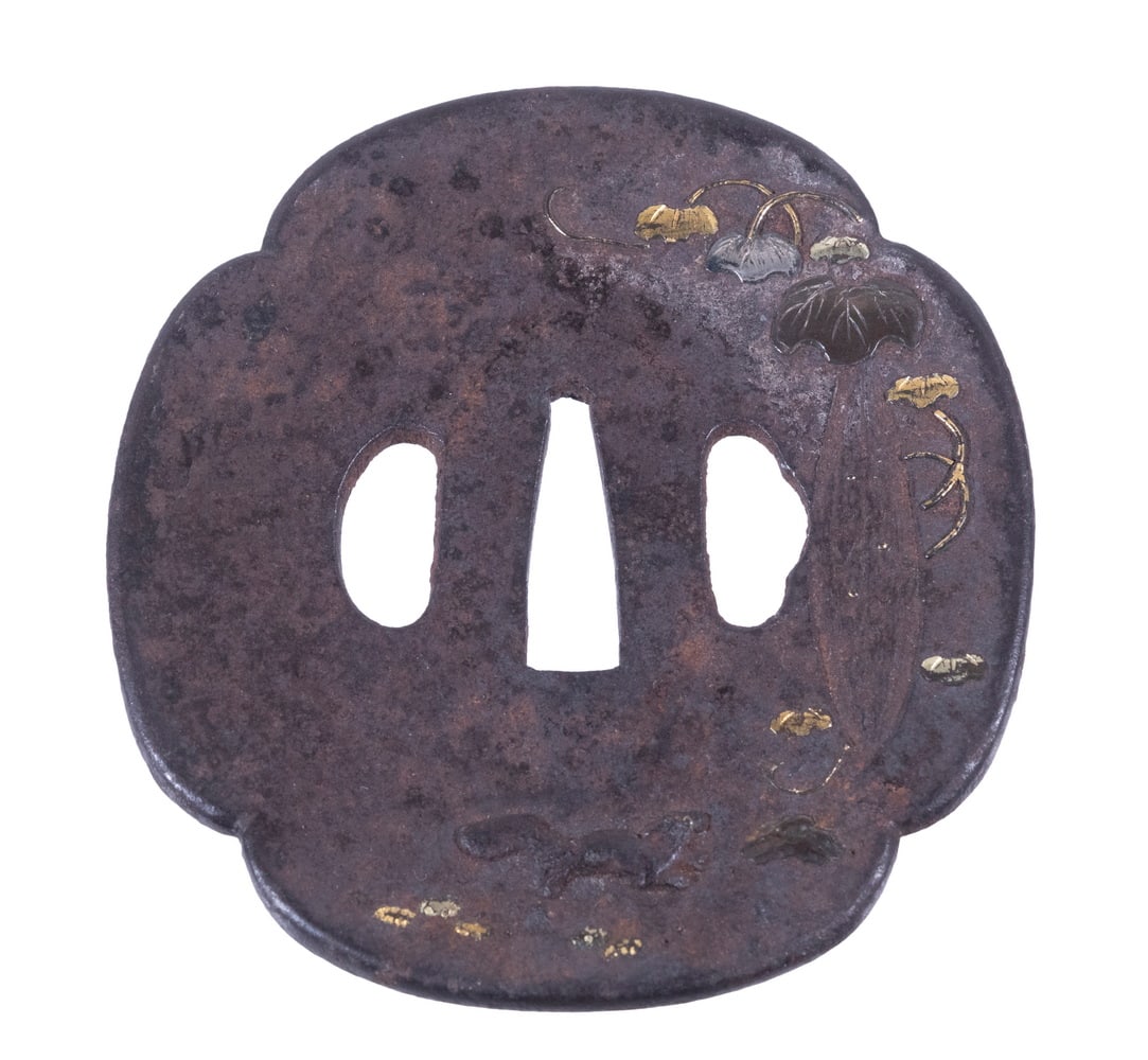 17TH C. JAPANESE EDO SWORD TSUBA: Iron, with gold, silver and copper inlay of ferret chasing rabbit, broadleaf ivy, fish in a river, Mokko Gata Tsuba shape with double Hitsuana, Edo Period (1600-1868). 3 3/8" x 3 1/8". Corroded.