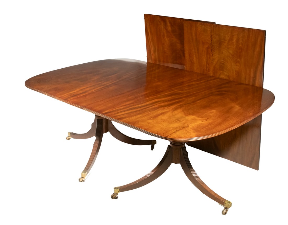 PERIOD DUNCAN PHYFE DINING TABLE: Period Double Pedestal Table in mahogany with classical fluted sabre legs having brass cap large casters. The two demi-lune tops are stored in the same rolling custom wooden case as the two leaves, th