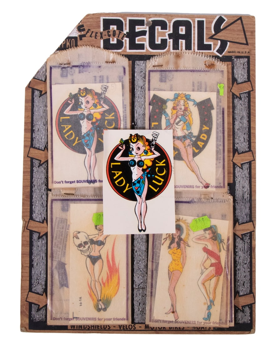 SALES DISPLAY OF CA 1950 RACY DECALS: (28) Pin Up Flex-Cote Decals remaining on display card from Impko, including: (1) Lady Luck (1 loose w/o glassine bag); (5) Lucky Lady; (4) Flaming Skull Lady; (9) Pair Girls. 3" x 4" decals on 12 3/4