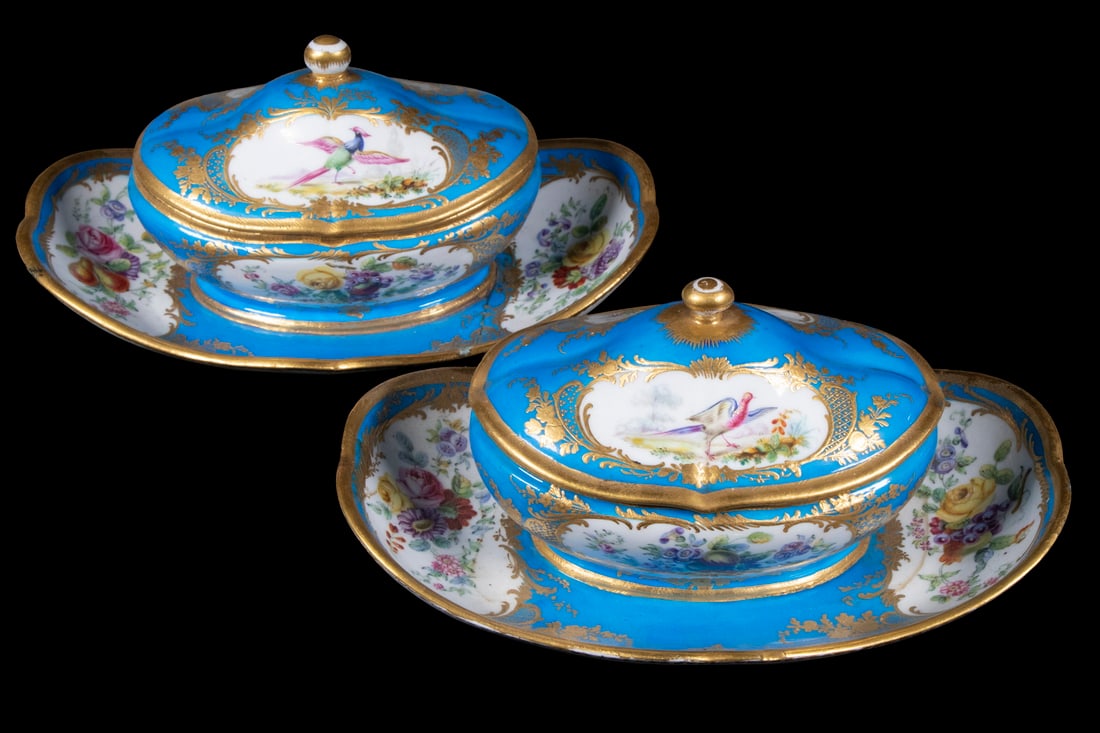 PR SEVRES STYLE PORCELAIN SAUCE BOWLS: Pair of Porcelain Lidded Oval Serving Bowls, with attached underplates, with hand painted bird and floral decoration on a medium blue ground, plus raised gilded flourishes, spurious blue entwined Ls m