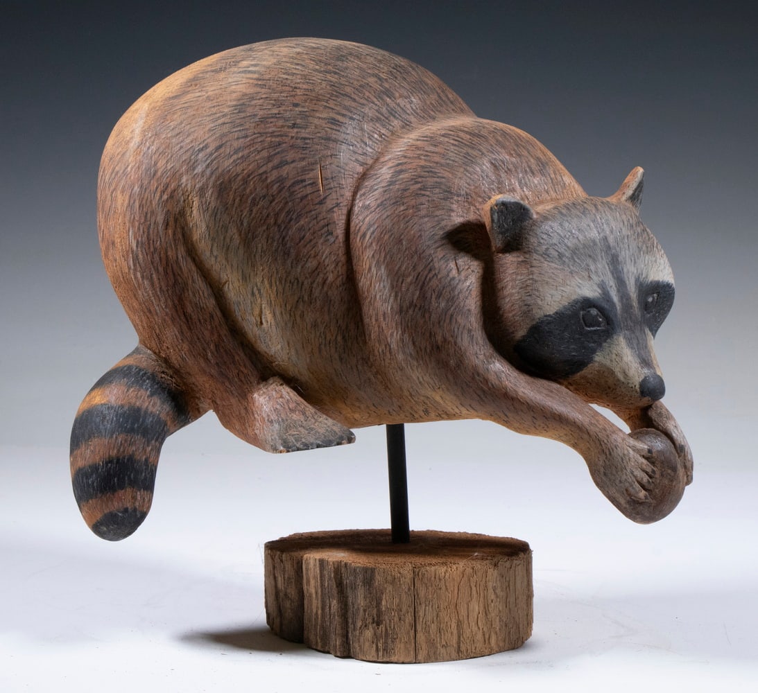 CARVED RACCOON BY D.W. DROWNE: Folk Art Carved and Painted Raccoon Figure, incised "Drowne" on base (likely for NH decoy and wildlife carver D.W. Drowne), on a custom wooden stand, 7" high, 11 1/2" x 6".