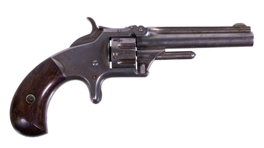 SMITH & WESSON MDL. 1, .22 SHORT: A tilt-up, single-action pocket revolver made by Smith & Wesson. The revolver features a round barrel with fluted cylinder, spur trigger and wood grip panels. The original finish has all but completel