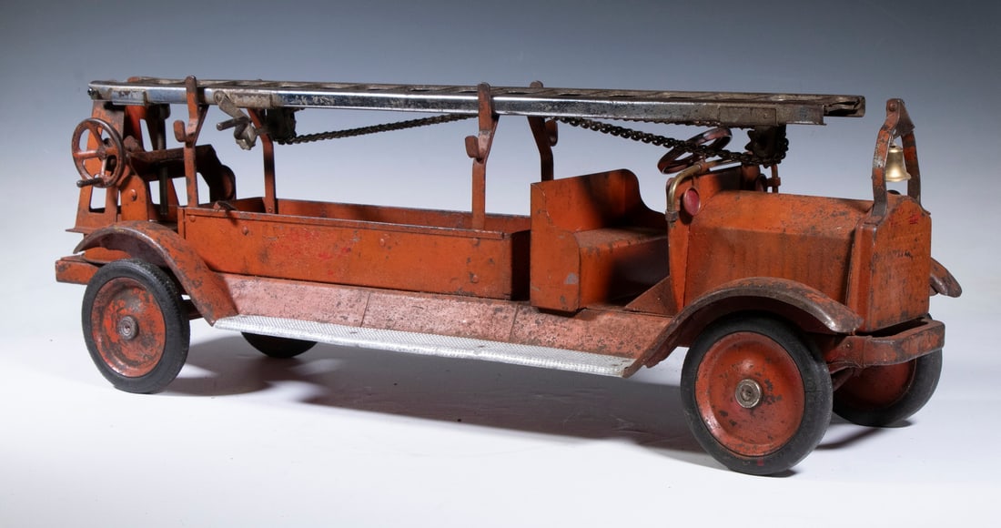 KEYSTONE PACKARD PRESSED STEEL TOY FIRE TRUCK: 1930s Aerial Ladder Truck by Keystone, with front mounted bell, top ladder in tact, with original wheels marked "Keystone, Boston" and balloon tires, 10" high, 30" wide. Paint losses, missing side lad