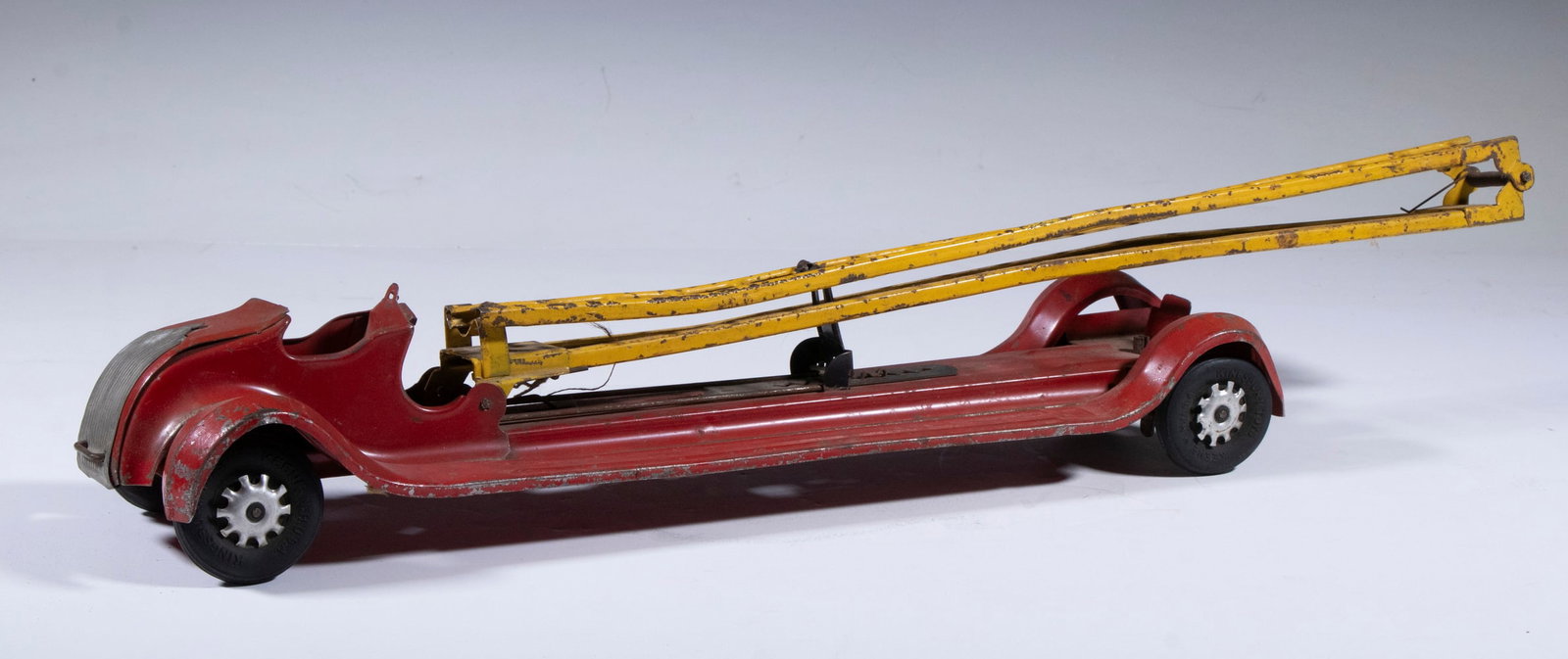 KINGSBURY TOY AERIAL LADDER TRUCK: 1920s Era Pressed Steel Fire Truck, by Kingsbury Toys (Keene, NH), originally with automatic extension ladder, 4 1/2" high, 23" wide. Ladder dents, extension feature not operating.