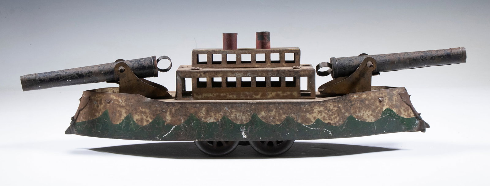 DAYTON HILLCLIMBER TOY BATTLESHIP: US Navy Dreadnought on Wheels, with counterweight drive by the Dayton Toy Co., ca. 1900, with deck mounted cannons, 6" high, 22 1/2" x 4 1/2". Paint losses; missing top masts and lifeboats.