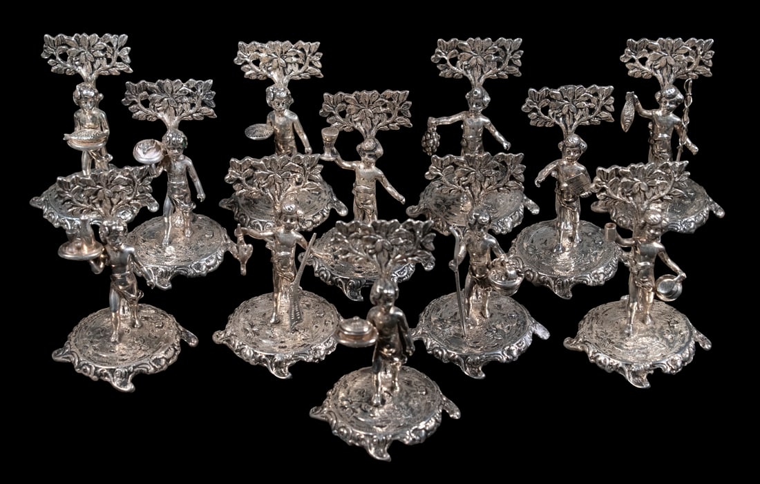 (12) FIGURAL STERLING SILVER PLACE CARD HOLDERS: Set of (12) Vintage Silver Table Accessories, by Binder Brothers, New York, each depicting a different standing Classical figure carrying a food-related item, each with engraved monogram to back, 2" h