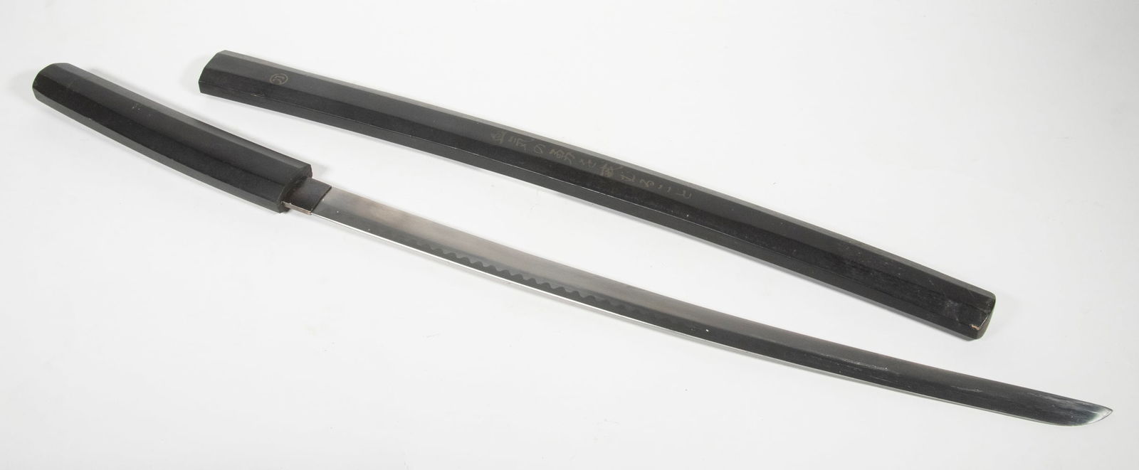 JAPANESE WAKIZASHI IN SAYA, LATE 20TH: Modern Fine Blade with regular serrated pattern hamon, steep kisaki, in black lacquer saya with gold inscription. 50 cm blade, 30 3/4" overall.