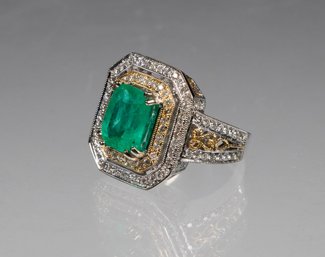 EMERALD, DIAMOND AND 14K WHITE GOLD LADIES RING: One electronically tested 14K white gold ladies cast emerald & diamond ring; featuring an emerald set within an inner yellow gold diamond set bezel, supported by an elaborate under gallery and open wo