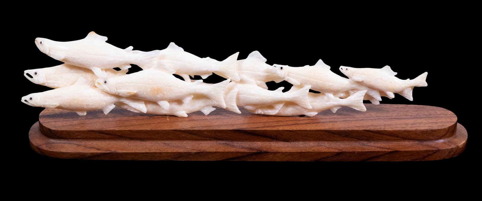 INUIT WALRUS IVORY CARVING OF FISH: A Run of Sockeye Salmon, well carved, reticulated, on wooden mount, loose on pins. 7 1/2" long figure. Converted dimensions: Length: 7 1/2 in. (19.1 cm.)