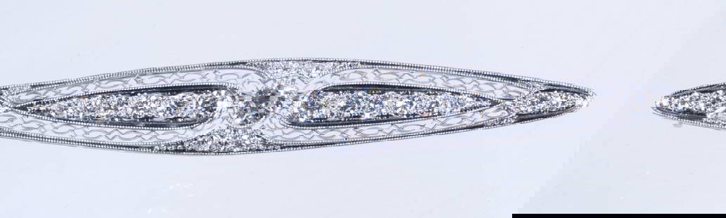 EDWARDIAN 18K WHITE GOLD AND DIAMOND BROOCH: 18K White Gold Filigree Bar Pin, centered with a large round faceted diamond flanked by two narrow panels - each set with six graduated faceted diamonds, and the edges set with tiny diamonds, 2 1/2" w
