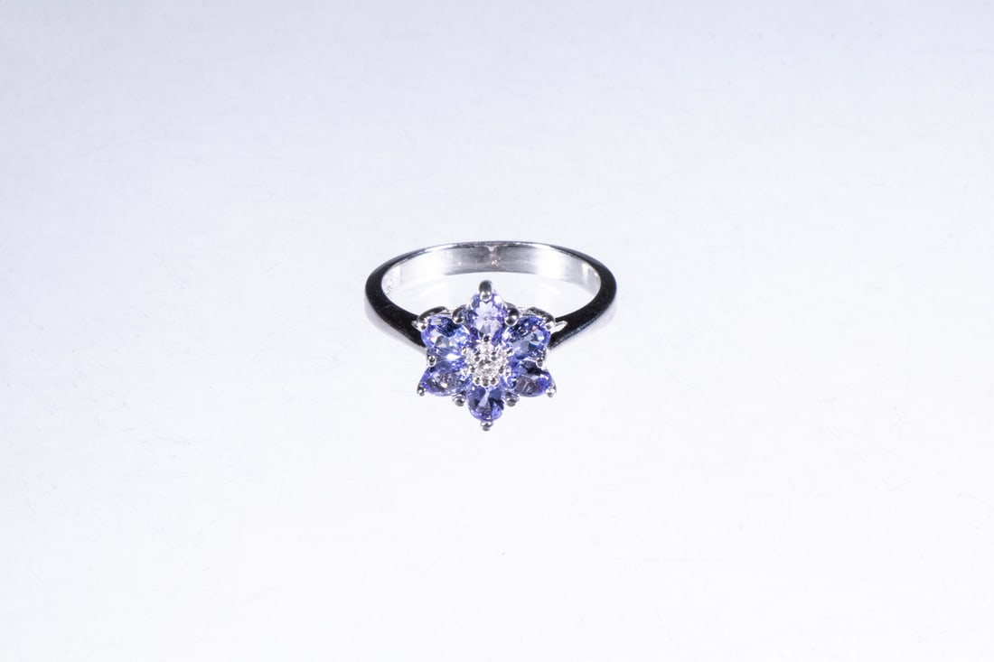 14K WHITE GOLD, IOLITE AND DIAMOND RING: Floral form design set with a central round diamond surrounded by (6) oval cut light blue iolites, stamped "14K", size 7; 2.3dwt. tw. Good condition. Dimensions Ring Size: 7