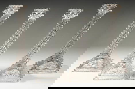 (4) SANDWICH GLASS COLUMN FORM CANDLESTICKS: Set of (4) Clear Glass Corinthian Column Form Candle Holders, ca. 1920s, each with beaded edge top, spiral decorated stem, raised cherub heads and urns on the square domed base.From the estate of Broo