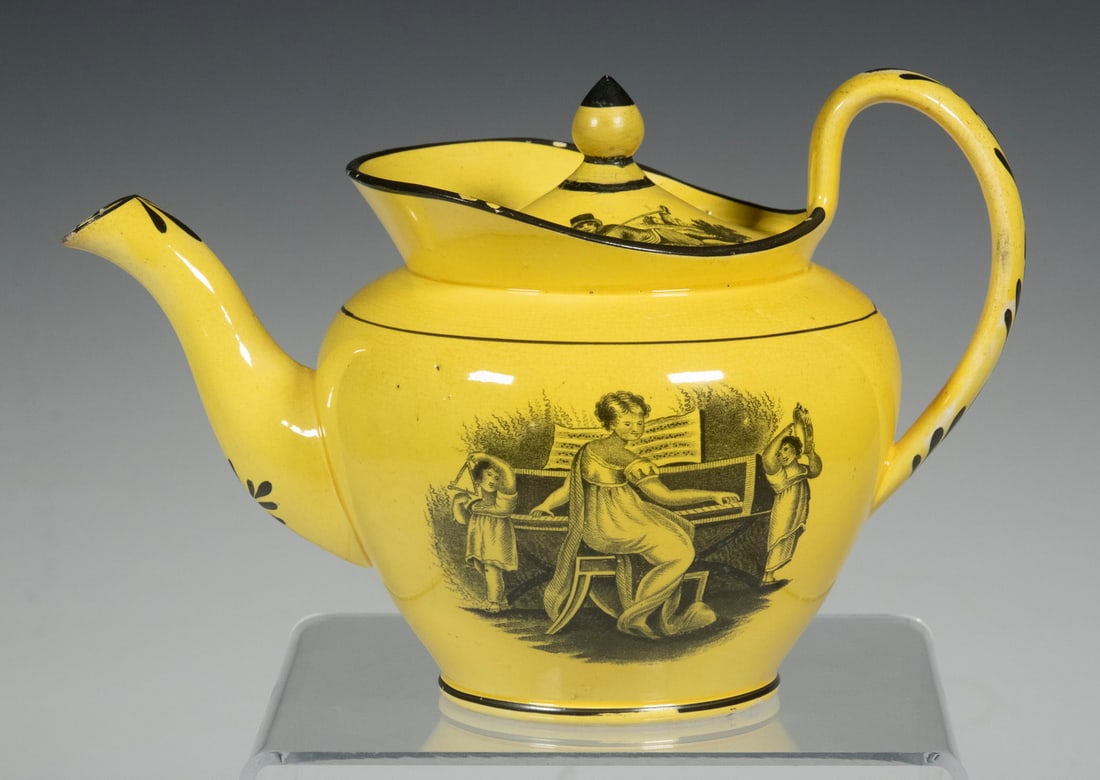 ENGLISH CANARY YELLOW TRANSFERWARE TEAPOT: Early 19th c. Yellow Ground Teapot, with front and back black transfer-printed decoration of children playing musical instruments, possibly by Sewell Pottery, Newcastle, unmarked. Spout chip; lid and