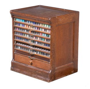 CIRCA 1900 DRY GOODS STORE SPOOL CABINET: Golden Oak Cabinet containing eight glass front spool drawers fitted with nickel plated pulls, over a single all wood drawer, panel sides and back. 25 x 21 x 17 in. (63.5 x 53.3 x 43.2 cm.)