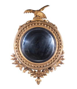 LARGE FEDERAL PERIOD GILTWOOD BULLSEYE MIRROR: Bold and Ornamental Bullseye Mirror, circa 1810, having a deep cove with ring of spheres, well-carved spread-wing American Eagle crest, deeply carved and gessoed applied themes of oak leaves with acor