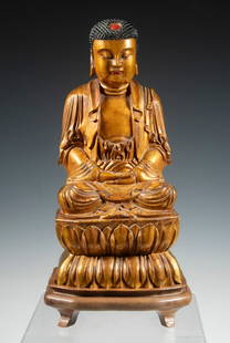CHINESE GILTWOOD SEATED BUDDHA FIGURE: Carved wood figure of a Buddha seated in dhyana mudra atop a double lotus pedestal, with serene expression, black curled hair, and a red urna at the forehead. Rich gilt surface with traces of red pigm