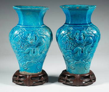 PR CHINESE TURQUOISE-GLAZED DRAGON VASES WITH HARDWOOD STANDS: Each vase molded in high relief with a three-clawed dragon among clouds, covered in a brilliant turquoise glaze with natural pooling in recesses, the glaze thinning at the rim and shoulder. Raised on