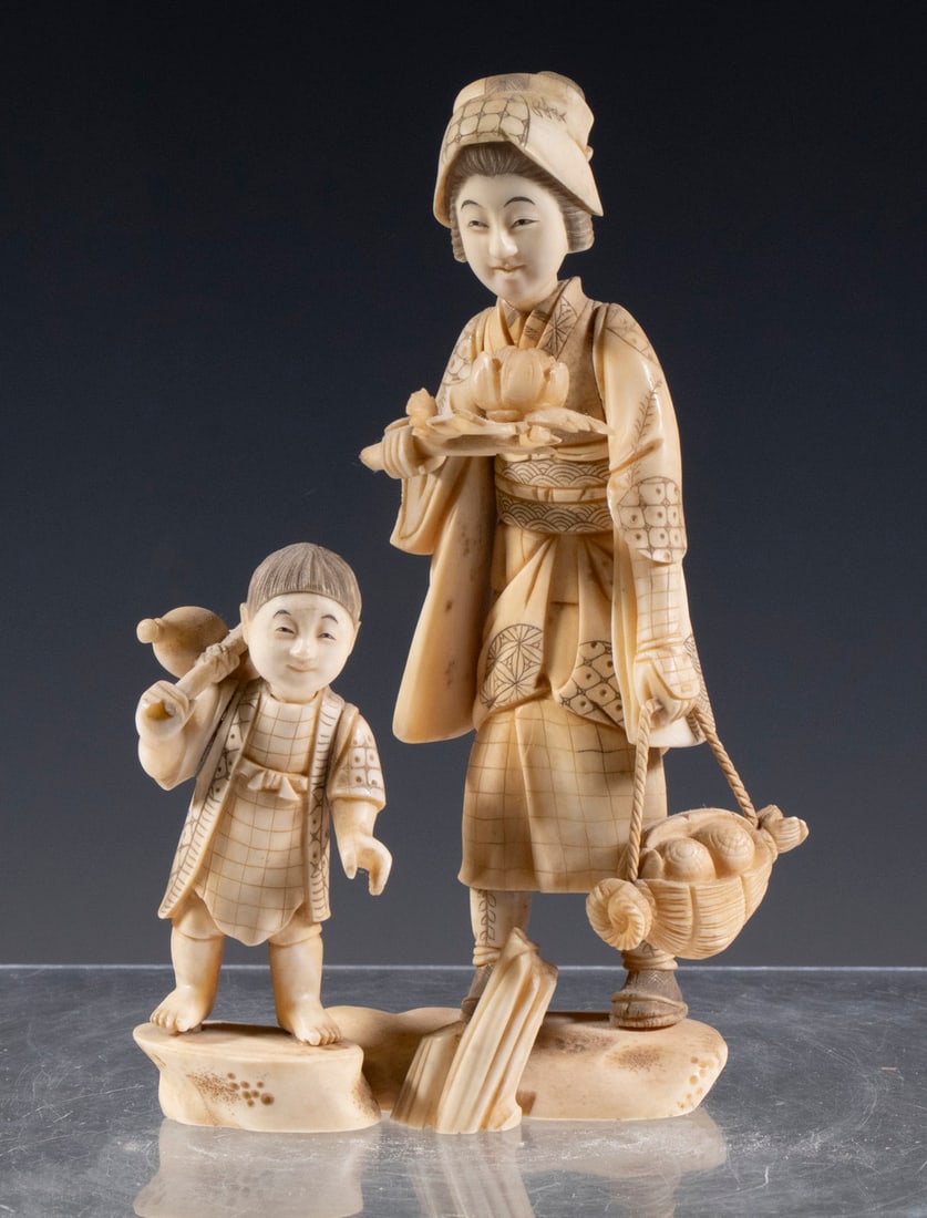 19TH C. JAPANESE MEIJI IVORY OKIMONO, SIGNED: Woman with Boy Traveling, she proffers an articulated lotus branch, signed on underside. 6 1/2 x 4 1/2 x 2 1/4 in. (16.5 x 11.4 x 5.7 cm.)