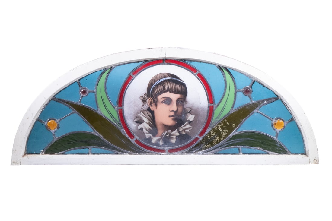 RARE LEADED GLASS JEWELED PORTRAIT ON TRANSOM, CA 1890: Gilded Age Fanlight Transom featuring a bust portrait of a young girl with white ruffled collar and blue hairband. 14 x 37 in. (35.6 x 94 cm.)