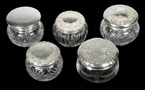 (5) STERLING TOP CRYSTAL POWDER JARS: Collection of (5) Vintage Cut Crystal Vanity Jars, with American sterling silver lids, assorted makers, four with repousse decoration, two with engraved monograms, one with hinged lid. 4.74 ozt. tw. L