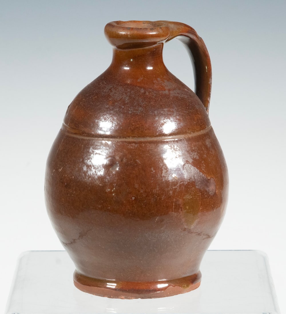 MAINE REDWARE JUG, ATTRIBUTED TO NORCROSS: MAINE REDWARE JUG, ATTRIBUTED TO NORCROSS Mid-19th c. Copper Glazed Jug, attributed to Matthias Norcross (Farmington, ME), with a tooled indentation below the shoulder, applied handle. Handle chip. Fr