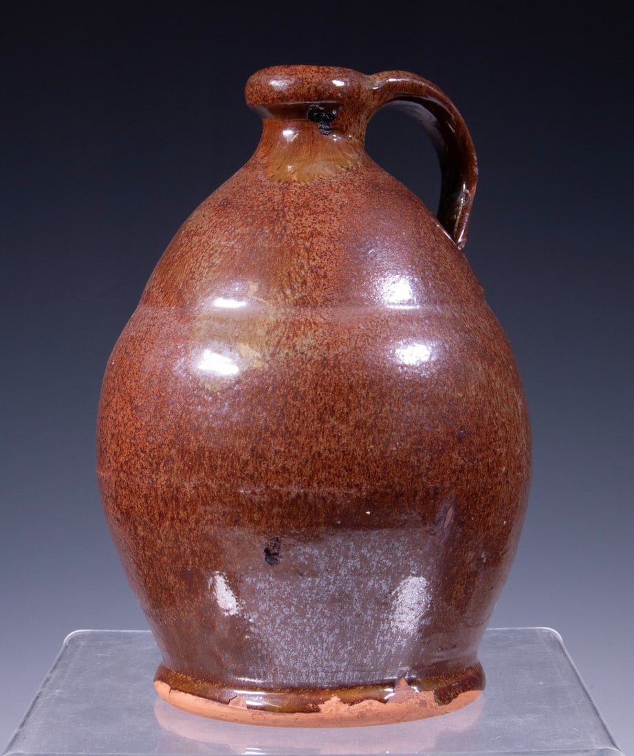 MAINE REDWARE JUG, ATTRIBUTED TO NORCROSS: MAINE REDWARE JUG, ATTRIBUTED TO NORCROSS Mid-19th c. Copper Glazed Jug, attributed to Matthias Norcross of Farmington, ME, with a tooled indentation below the shoulder, applied handle. Foot and handl