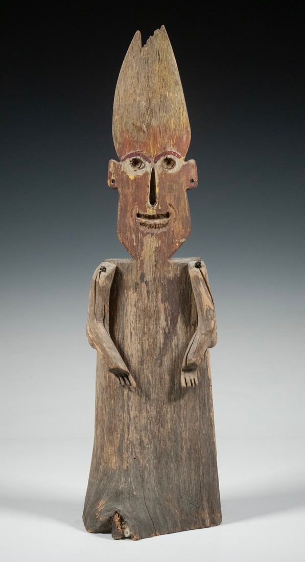 FOLK ART WOOD FIGURE WITH JOINTED ARMS: FOLK ART WOOD FIGURE WITH JOINTED ARMS A primitive carved folk art figure, crafted from weathered wood with a tall pointed head, painted facial features, and articulated arms attached by nails. The to