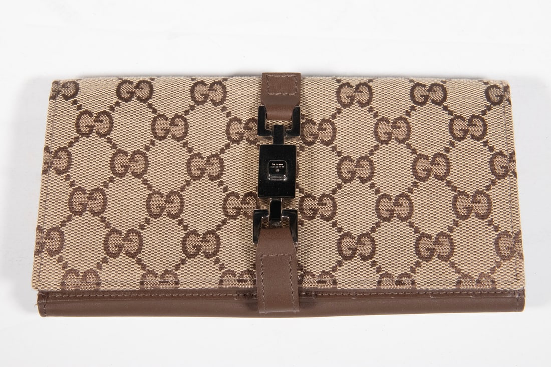 GUCCI GG CANVAS AND LEATHER WALLET WITH METAL CLASP, ITALY: A vintage Gucci bifold wallet crafted in GG monogram canvas with brown leather trim and interior. The front features a distinctive metal clasp engraved "GUCCI" and "Italy". Interior stamped "GUCCI / m