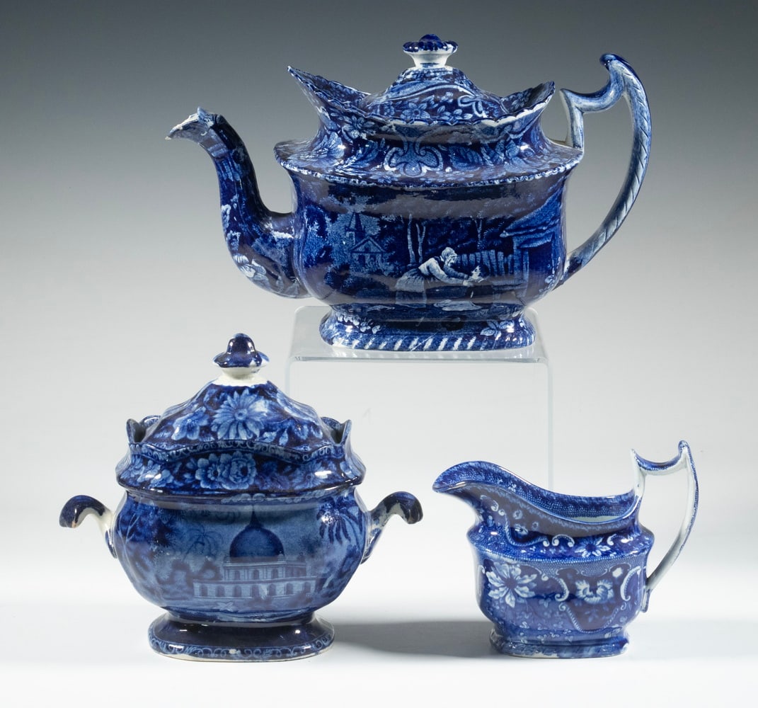 (3) STAFFORDSHIRE DARK BLUE TRANSFERWARE TEA SERVICE, 19TH CENTURY: A partial Staffordshire dark blue transferware tea service, comprising a teapot, covered sugar bowl, and creamer. Each piece is decorated in deep cobalt blue underglaze with floral borders; the sugar 