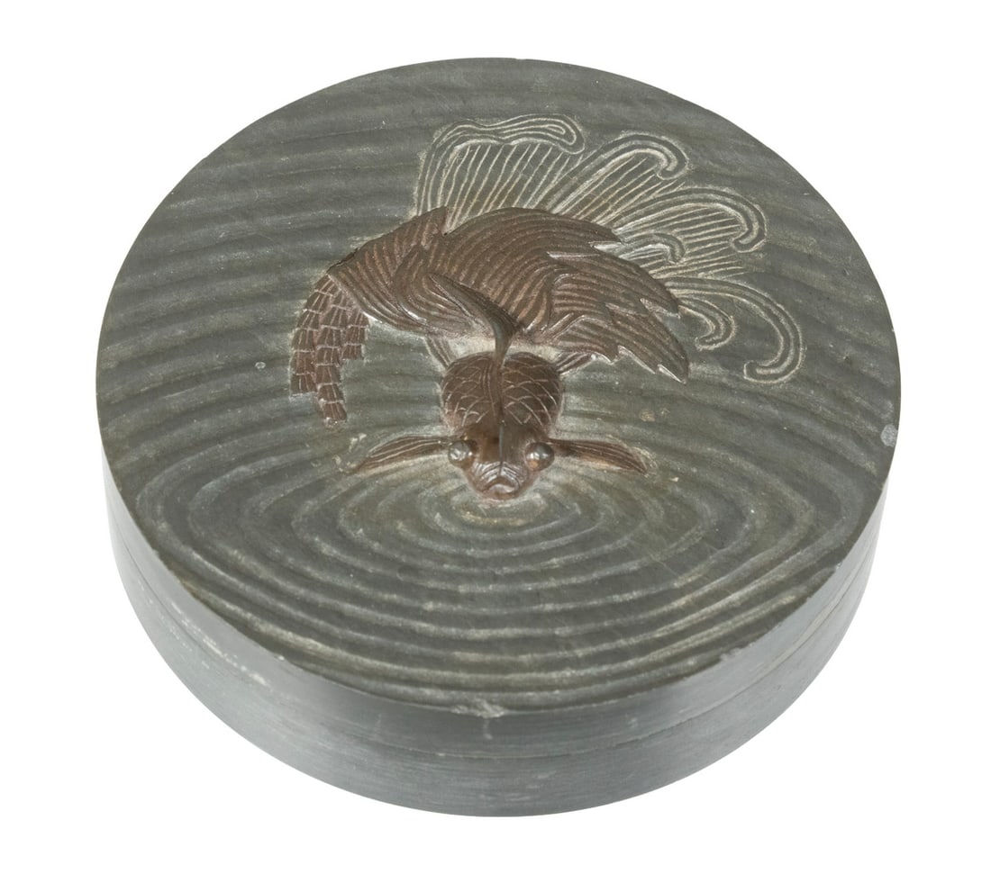JAPANESE CARVED INKSTONE WITH COVER: The lid finely carved in high relief with a gold fish gliding through rippling water. Minor surface wear, overall good condition. 4 x 4 in. (10.2 x 10.2 cm.)