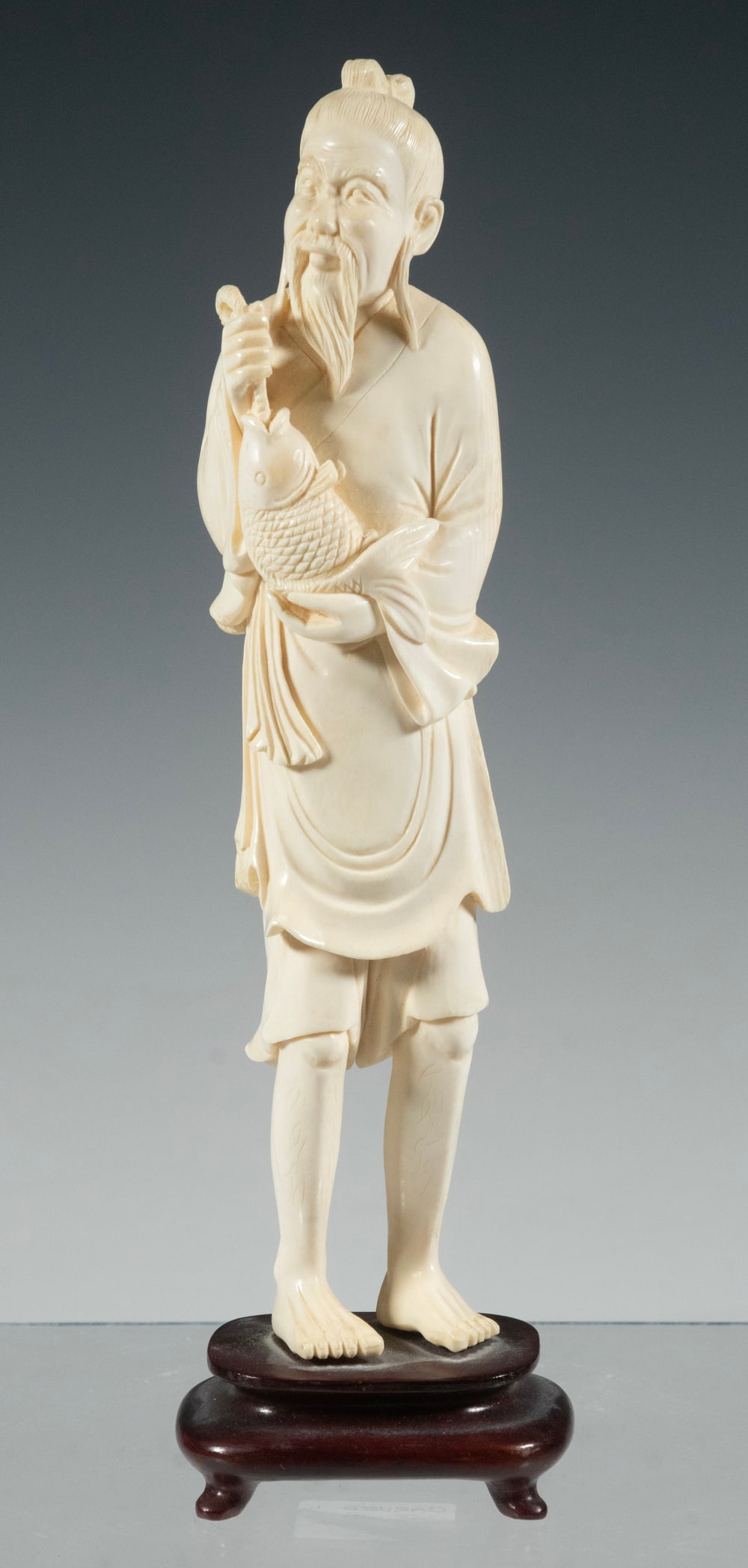 19TH C. CHINESE IVORY CARVING: Standing Figure of Bearded Man holding freshly caught Carp, his robe hitched above his knees, mounted on later stand. 9 x 2 x 1 in. (22.9 x 5.1 x 2.5 cm.)