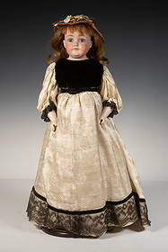 FRENCH FASHION DOLL: Bisque head with blue glass eyes, pate red hair, straw hat with flowers, in black velvet and white silk dress, Height: 18 in. (45.7 cm.)