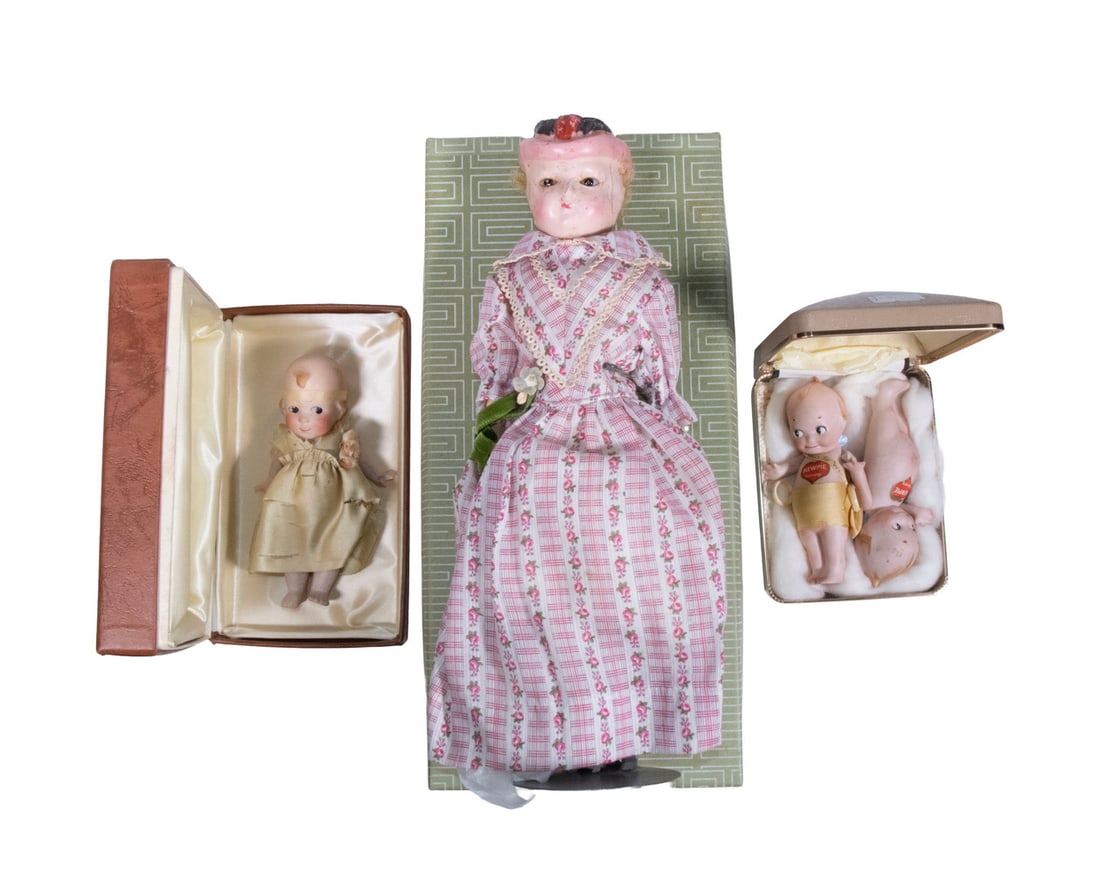 PAIR & SINGLE KEWPIE DOLLS IN HARD CASES PLUS 19TH C DOLL: German Bisque Dolls, one has a gold dress and a sash that reads "She's for Women", a Suffragette for Voting Rights, 4" tall. PLUS 5" Kewpie; PLUS 12" Waxed Compo Head gass eye Girl in pink cotton chin