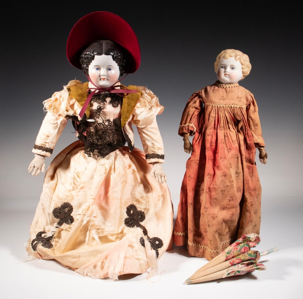 (2) LARGE LATE 19TH C. DOLLS: Including: 22" Porcelain head Jenny Lind with kid leather body, leather boots, sun bleached pink silk dress with black frogging appliques, parasol; PLUS 18" Bisque head blonde in sunfaded brick colore