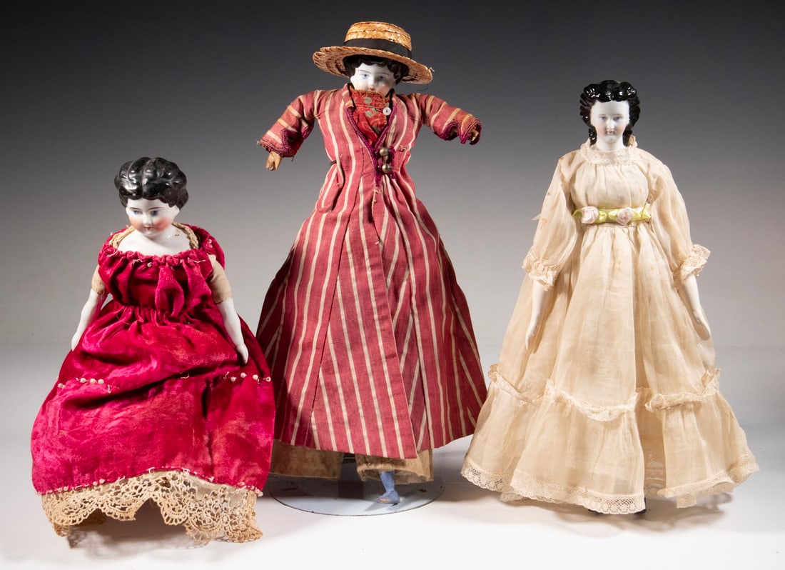 (3) 14" LATE 19TH C. JENNY LIND DOLLS: All porcelain head, including: Heavy red & white duster with straw hat (missing leg); PLUS Wine velvet fancy dress with pearls, lace trim, beribboned porcelain legs; PLUS White sheer taffeta summer dr