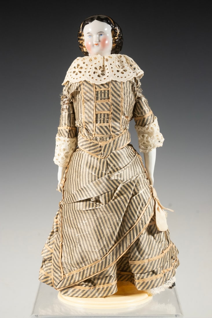 PERIOD JENNY LIND PORCELAIN HEAD DOLL: 11" with original grey and white polished cotton Victorian dress with lace trim. Height: 11 in. (27.9 cm.)