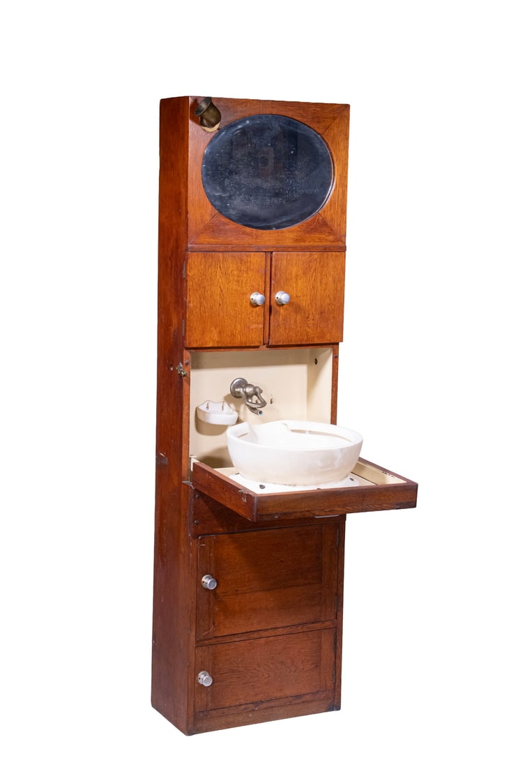 ANTIQUE MAHOGANY & OAK YACHT SINK: Floor Standing Marine Vanity Cabinet, with interior metal water tank, oval mirror, two door storage area with single interior shelf, fall front oak panel with interior mounted spigot, porcelain basin 