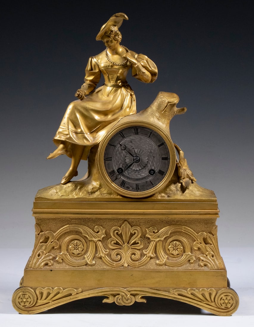 FRENCH GILT BRONZE FIGURAL MANTEL CLOCK: 19th c. Clock, topped with the figure of a young woman sitting cross-legged atop a tree stump, time and strike movement with pendulum and key, textured metal dial with Roman numerals, set on a fancy s