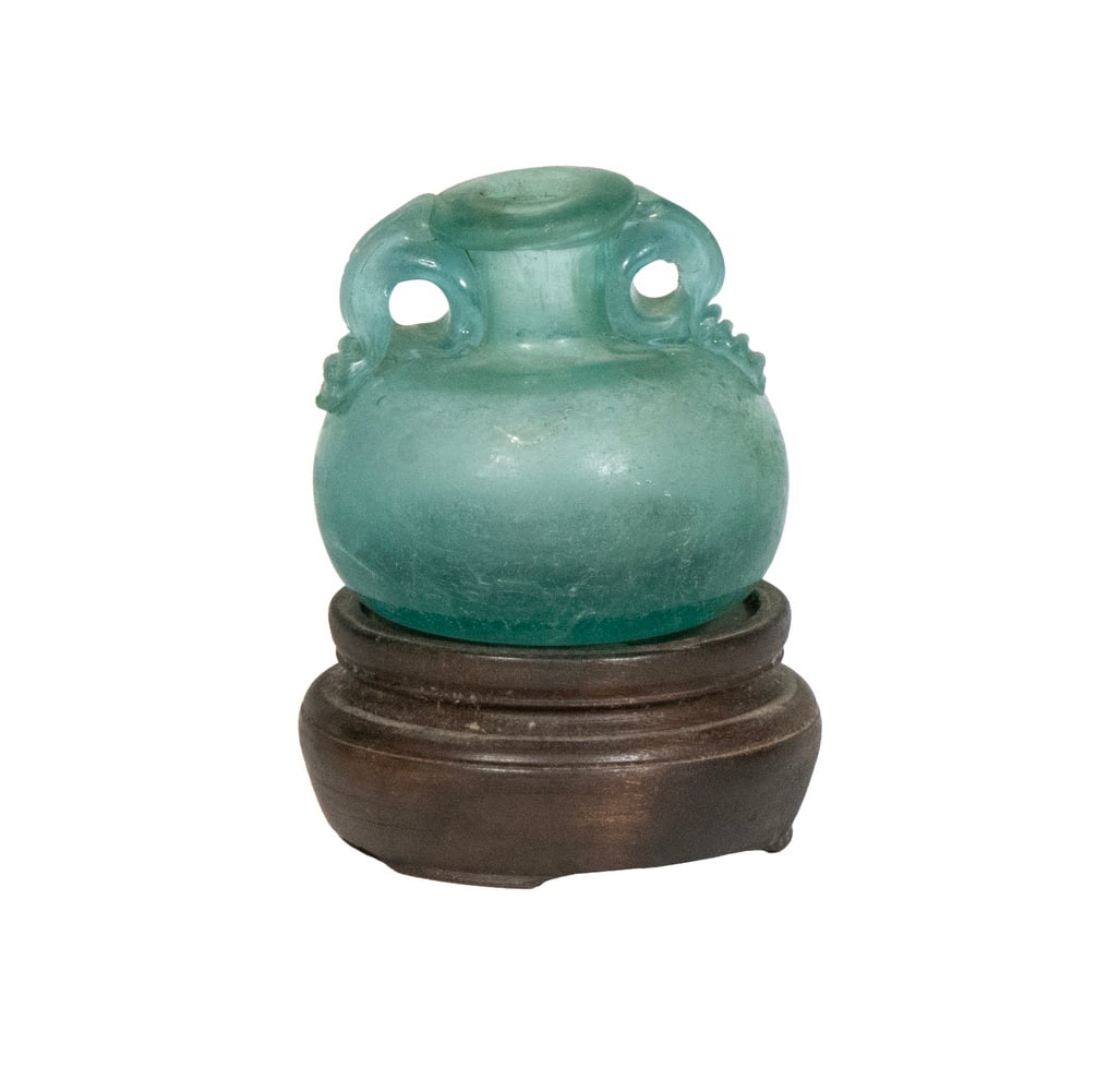SMALL ROMAN GLASS JAR: Bulbous Green Glass Vessel, ca. 2nd-3rd c. CE, with flat rim and two circular side handles, with wooden display stand, jar only: 2 1/4" high. 2 1/4 in. (5.7 cm.)