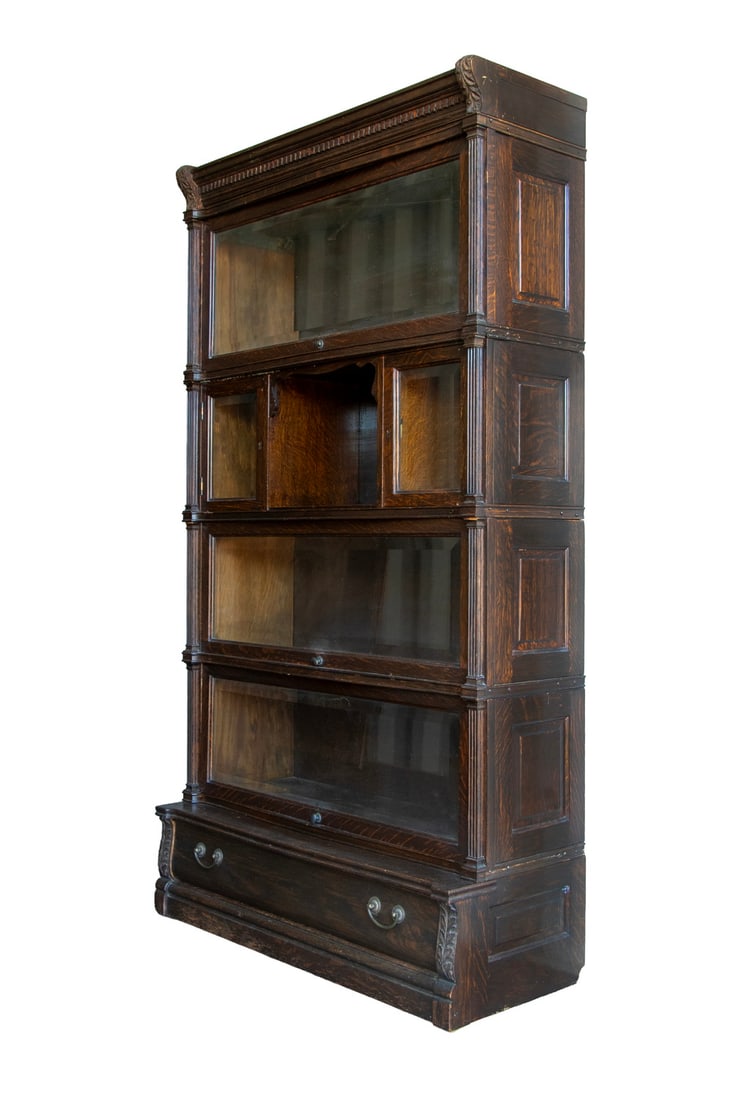 SIX PART OAK & BEVELED GLASS BARRISTERS BOOKCASE BY GLOBE WERNECKE: Dark Oak with beveled glass, fluted columns, center open cubby, leaf-carved brackets, shallow drawer in base. 66 x 36 x 13 in. (167.6 x 91.4 x 33 cm.)