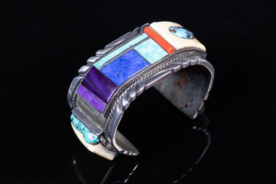ARNOLD GOLDSTEIN & ALBERT BERNALLY INLAID STERLING CUFF BRACELET, 1986: Marked “A. BERNALLY” and signed “A. Goldstein 1986.” A bold and heavy Navajo-style sterling silver cuff bracelet featuring raised inlay of turquoise, coral, lapis, and bones. T