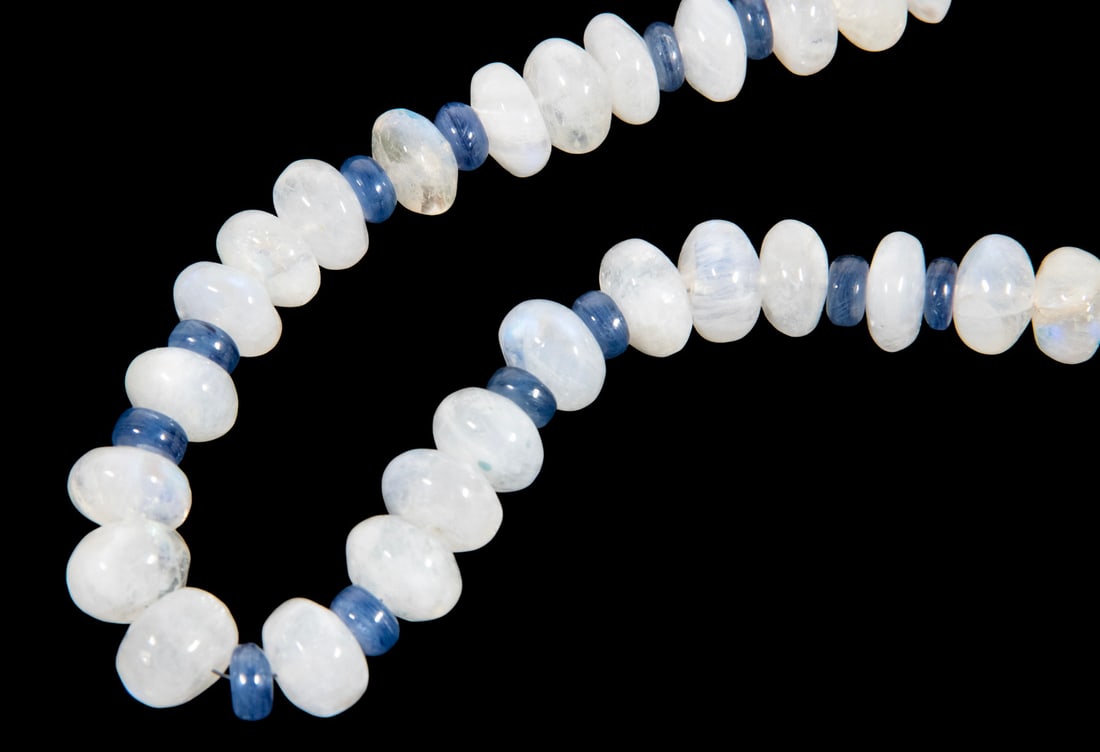 MOONSTONE AND KYANITE BEAD NECKLACE WITH SILVER FITTINGS: A hand-strung necklace composed of (41) polished moonstone rondelle beads (each approx.15mm x 18mm) interspaced with (18) kyanite spacers (each approx. 8mm x 4mm), accented with decorative silver caps