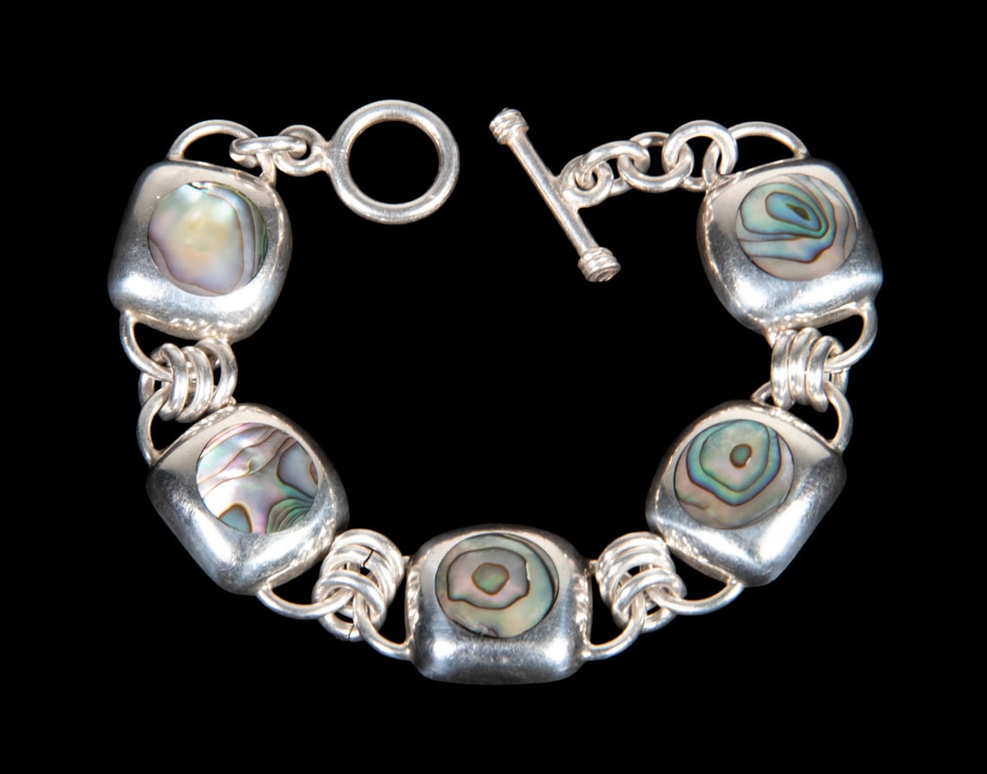 MEXICAN STERLING SILVER AND ABALONE SHELL BRACELET: A Mexican bracelet composed of (5) square sterling silver links, each bezel-set with a polished abalone shell panel showing iridescent green, purple, and blue hues. Completed with a toggle clasp. Stam