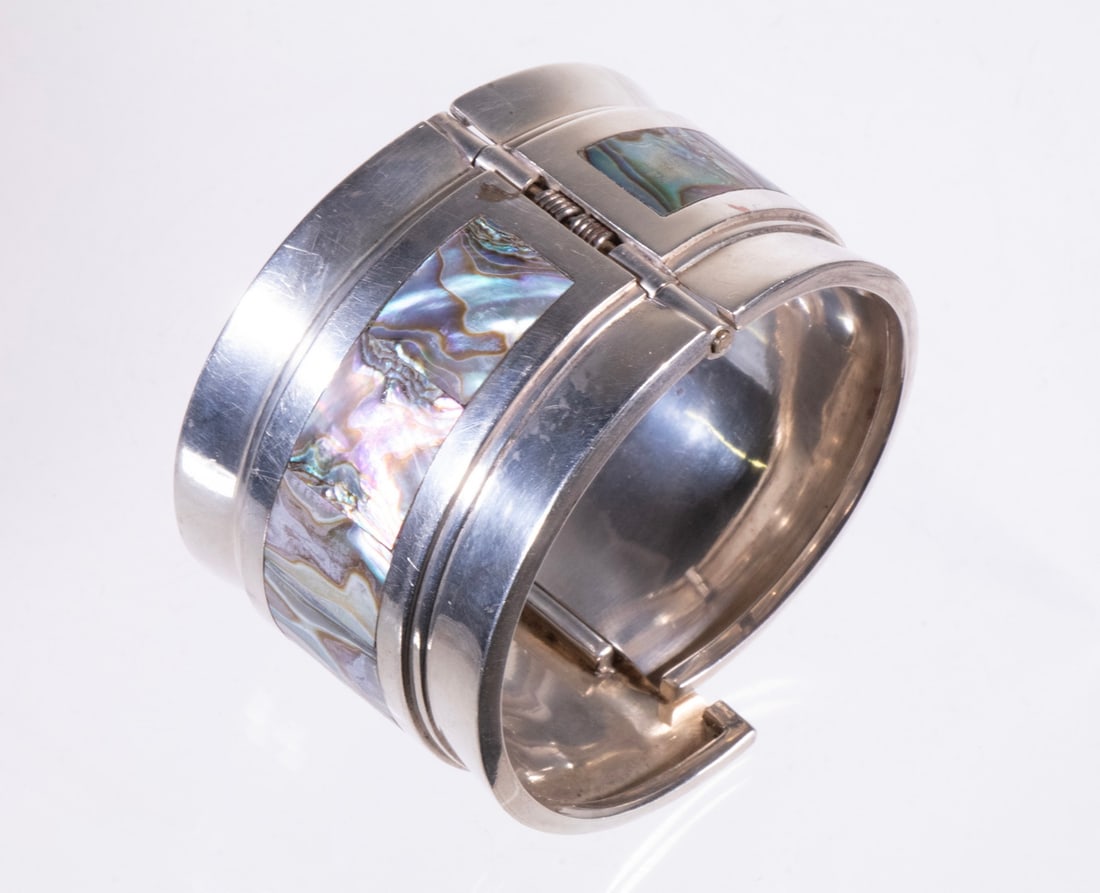 MEXICAN TAXCO SILVER AND ABALONE HINGED BRACELET: A wide sterling silver cuff with inset abalone shell panels, hinged construction. Stamped Mexico TC-01; 925, indicating a Taxco workshop. 3.0 ozt total weight. Overall good condition.